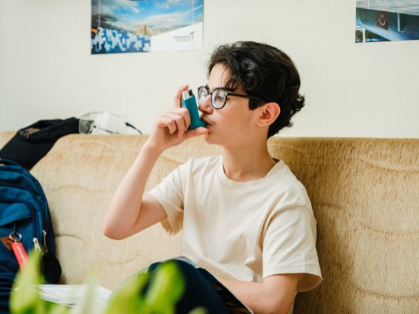 A child using an inhaler to manage their asthma symptoms comfortably at home