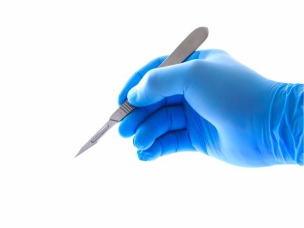 The sharp blade of the scalpel is visible while the surgeon is using it